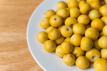 High resolution photo of fresh nance berries served on a simple white plate over wood, perfect for...