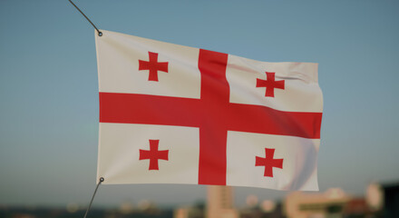 Georgian flag hanging outdoors against blue sky and cityscape. National flag of Georgia waving in urban setting. Independence Day of Georgia. 26 May.