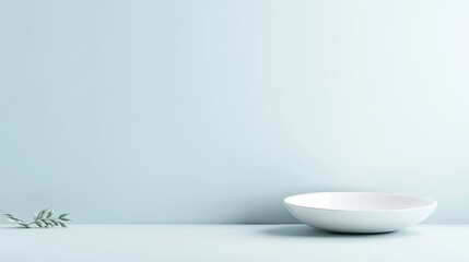 Simple, minimalist, light blue background with a white bowl and small sprig