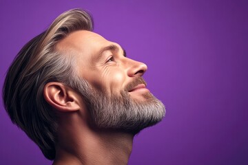 Fototapeta premium Chic men's textured crop haircut - midlife white man with blond hair. A studio glamour portrait of a confident man. Visual idea art of style for aging men. Purple solid background.