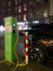 An electric car parked on the side of the road charging at night.
