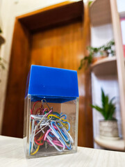 A clear box filled with paper clips sitting on top of a table