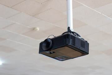 A projector hanging from the ceiling in a room