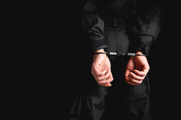 Fototapeta premium Man in uniform hands in steel handcuffs. Corruption in law enforcement, man caught breaking the law