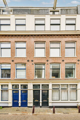 Fototapeta premium an old brick building in amsterdam, with blue doors on the front and windows open to let you into your home