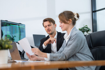 Colleagues engaged in a discussion over documents in a modern office environment during daytime hours