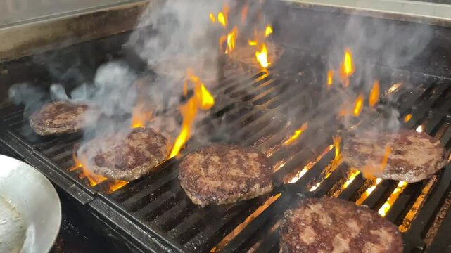 cooking burgers on a flame grill in a restaurant kitchen