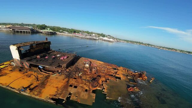 A low-altitude FPV flyby captures rusted shipwrecks along the Opol Broadwalk coastline in Cagayan de Oro, Philippines, contrasting decaying vessels with the tropical seascape.