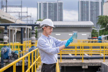 Engineer take water from wastewater treatment pond to check the quality of the water after going...