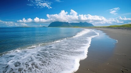 Naklejka premium Peaceful ocean waves on a sunny beach with mountain view