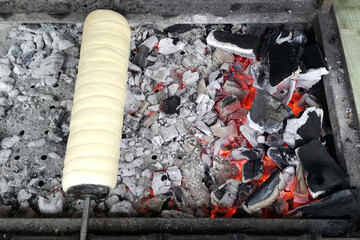 Terdelik, spiral-shaped confection wrapped around cylindrical shape, baking over coals. Traditional street treat at festivals and fairs in Czech Republic, Romania, Hungary and other European countries