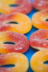 Close-Up of Sugar-Coated Jelly Peach Candy Rings, Shallow Depth of Field, Blue Background