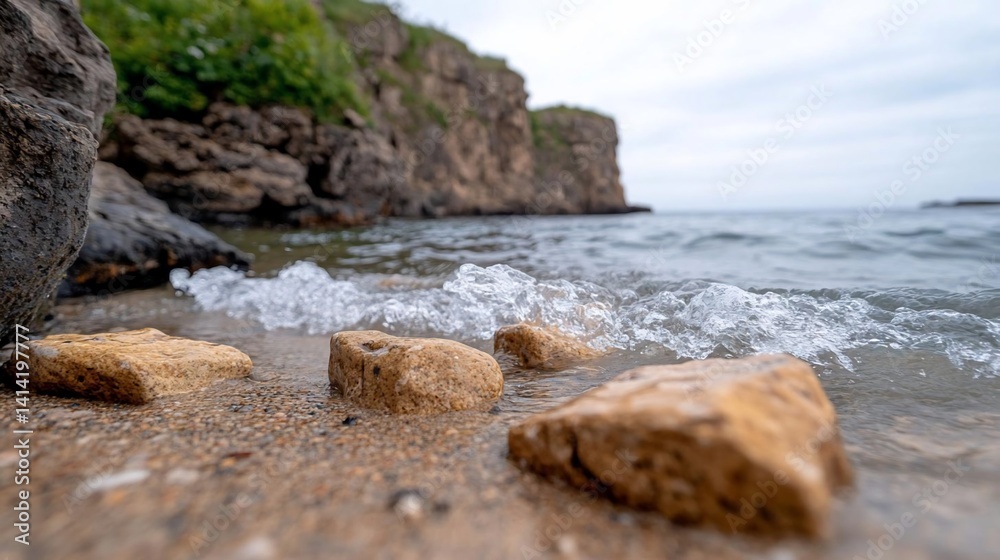 Poster close-up view of water gently lapping against the shoreline highlighting weathered rocks and foamy w