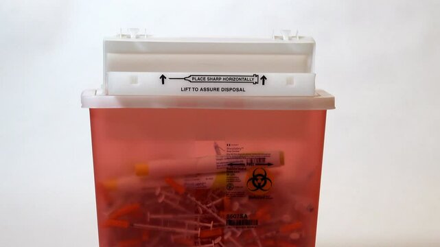 Close-up of injection pen disposed of into a large sharps container.