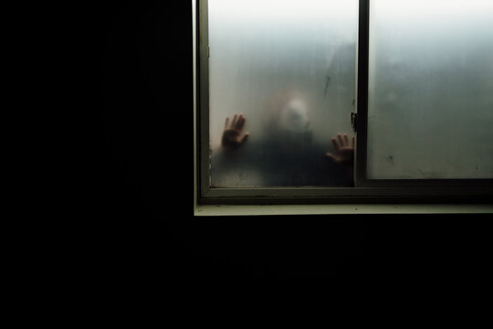 Creepy clown looks to unlock foggy window from the outside of home