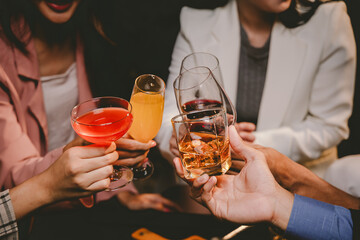 Cheerful group of stylish adults toast with whiskey at a luxurious bar, enjoying nightlife,...