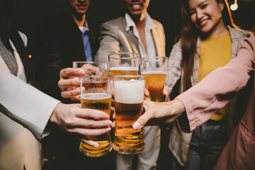 Happy group of friends toast with draft beer at a lively pub, celebrating friendship, fun, and festive moments together indoors.