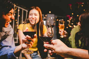 oyful young adults toast with wine glasses at a festive indoor party, celebrating friendship, holidays, and special moments together.