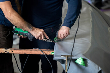 A worker uses an industrial heat sealer to join seams on a vinyl product at a manufacturing facility for industrial containers.
