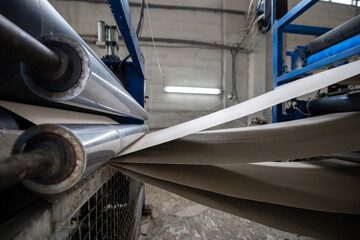 A production line for gluing thin sheets of paper from rolls at a bookbinding cardboard production facility. The company uses recycled material (waste paper) to make book covers.