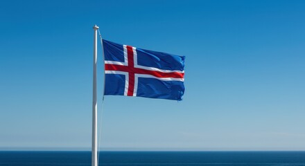 Fototapeta premium Icelandic Flag Waving Proudly by the Ocean Under a Clear Blue Sky A Majestic View of the Icelandic Flag