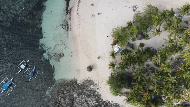Upward drone lift showcasing a tropical island in Philippines with white beach and palm trees.