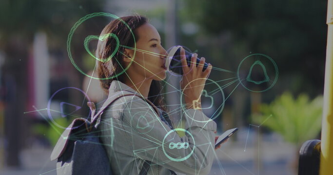 Image of network of social media icons over happy biracial woman drinking coffee in street