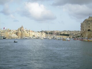 Obraz premium Scenic view of valletta waterfront with boats under cloudy sky in malta