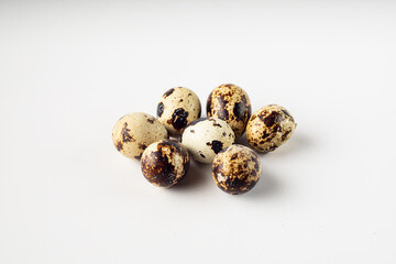 Fototapeta premium A close-up shot of seven speckled quail eggs arranged on a clean, white background.