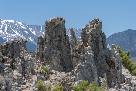 Unique rock formations rise against snow-capped mountains in a clear blue sky in the eastern Sierra Nevada