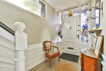 A stylish entryway showcasing a beautiful stained glass door and classic furnishings, creating a welcoming atmosphere in a well-decorated home.