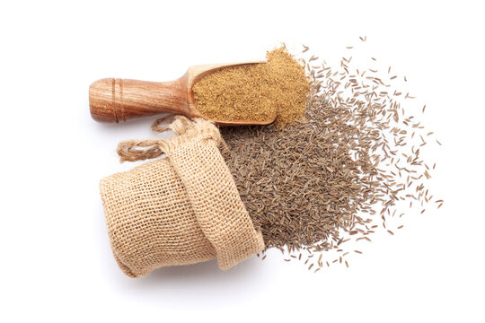 A scoop of organic Caraway seeds (Carum carvi) powder, along with whole Caraway seeds spilled out from a jute bag. Isolated on a white background.