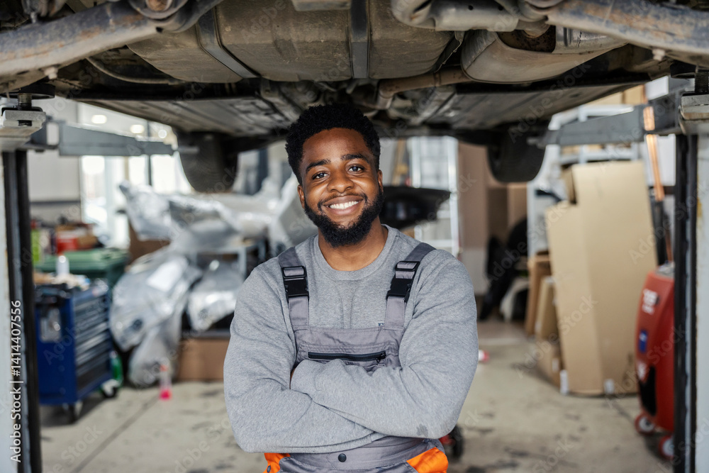 Poster portrait of interracial auto mechanic worker standing under chassis with arms crossed and smiling at