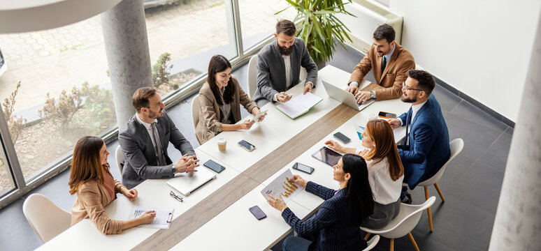 Top view of group of businesspeople sitting at boardroom and discussing data analytic. - Powered by Adobe