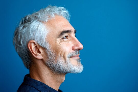 Fashionable men's short dreads haircut - midlife white man with white hair. A stylish male making a statement. Visual idea of style for aging men. Blue solid background.