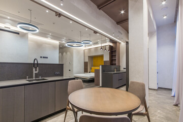 Interior design of a modern studio apartment with an open layout and division into zones. Elegant furniture, stylish lamps.