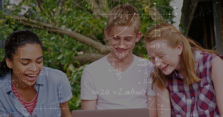 Image of mathematical equations over students using laptop