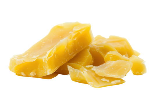Golden beeswax pieces arranged artistically on a clean white surface, showcasing natural texture