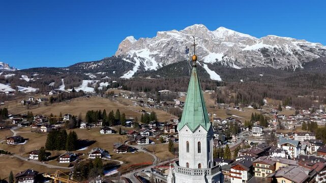 aerial around main old cathedral church of Cortina d'Ampezzo in the italian dolomites mountains
