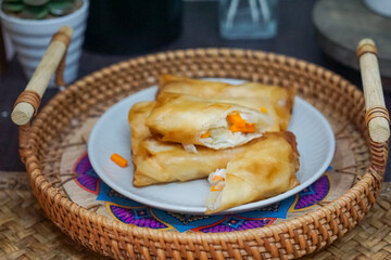 Delicious golden spring rolls displayed in a wicker basket on a plate, filled with fresh...