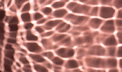 Mediterranean pink terracotta color plaster background with under water sun shadows.