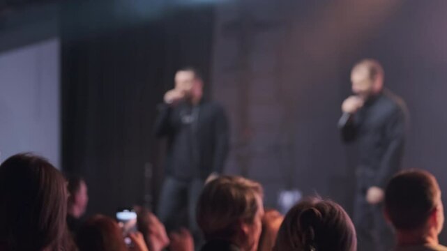 Live performance of rap artists on stage with a lively and enthusiastic fan audience.