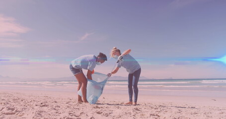 Image of lights over diverse couple in face masks picking up rubbish from beach