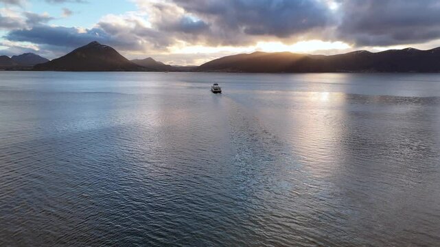 A car ferry crossing Sulafjord at sunset with mountains in the background near Aalesund, Norway