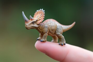 Fototapeta premium Adorable Miniature Dinosaur Toy Figurine Brown Prehistoric Reptile Model Small Dino on Fingertip Cute Jurassic Creature Playful Animal Toy Wildlife 