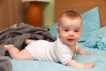 Fototapeta premium A small beautiful baby is dressed in a diaper and lies on the bed.
