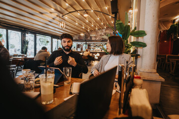 Two business coworkers share ideas while seated at a stylish cafe, demonstrating collaboration, engagement, and a professional yet relaxed atmosphere.