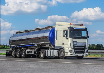 Truck with chrome tanker moves along country road