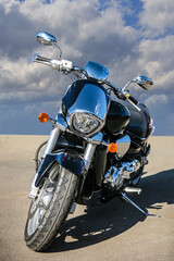 Obraz premium Motorcycle on asphalt against cloudy sky.