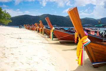 The line of Traditional Thai long-tail boat moor on the beach at the seaside area in the daytime is fresh and clear sky. Beautiful and natural Landscape. Traditional vehicle on water of Thailand.